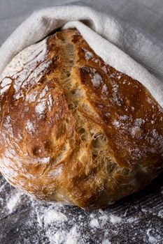 Close-up of a freshly baked artisan sourdough bread resting on a floured surface.