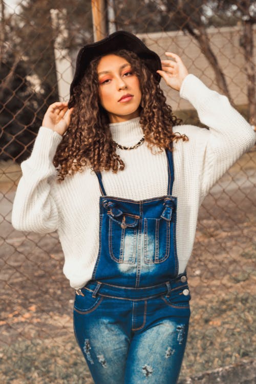 Woman in White Long Sleeve Sweater Near Fence