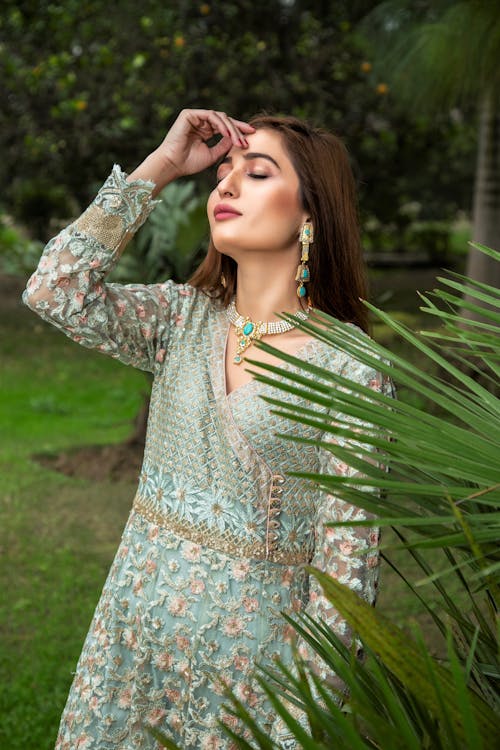 A Woman Feeling the Breeze while Standing Near Green Leaves