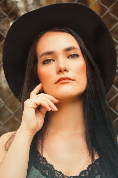 Free Elegant portrait of a woman with a black hat, posing thoughtfully outdoors. Stock Photo
