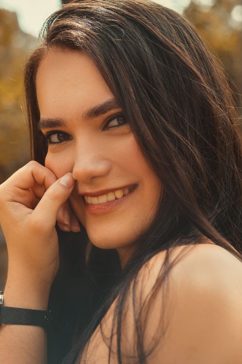 Free Close-up portrait of a smiling woman touching her face, outdoors. Stock Photo