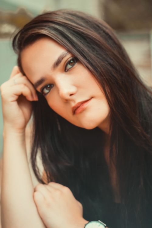 Free A thoughtful young woman with dark hair posing for a close-up portrait. Captivating and artistic. Stock Photo