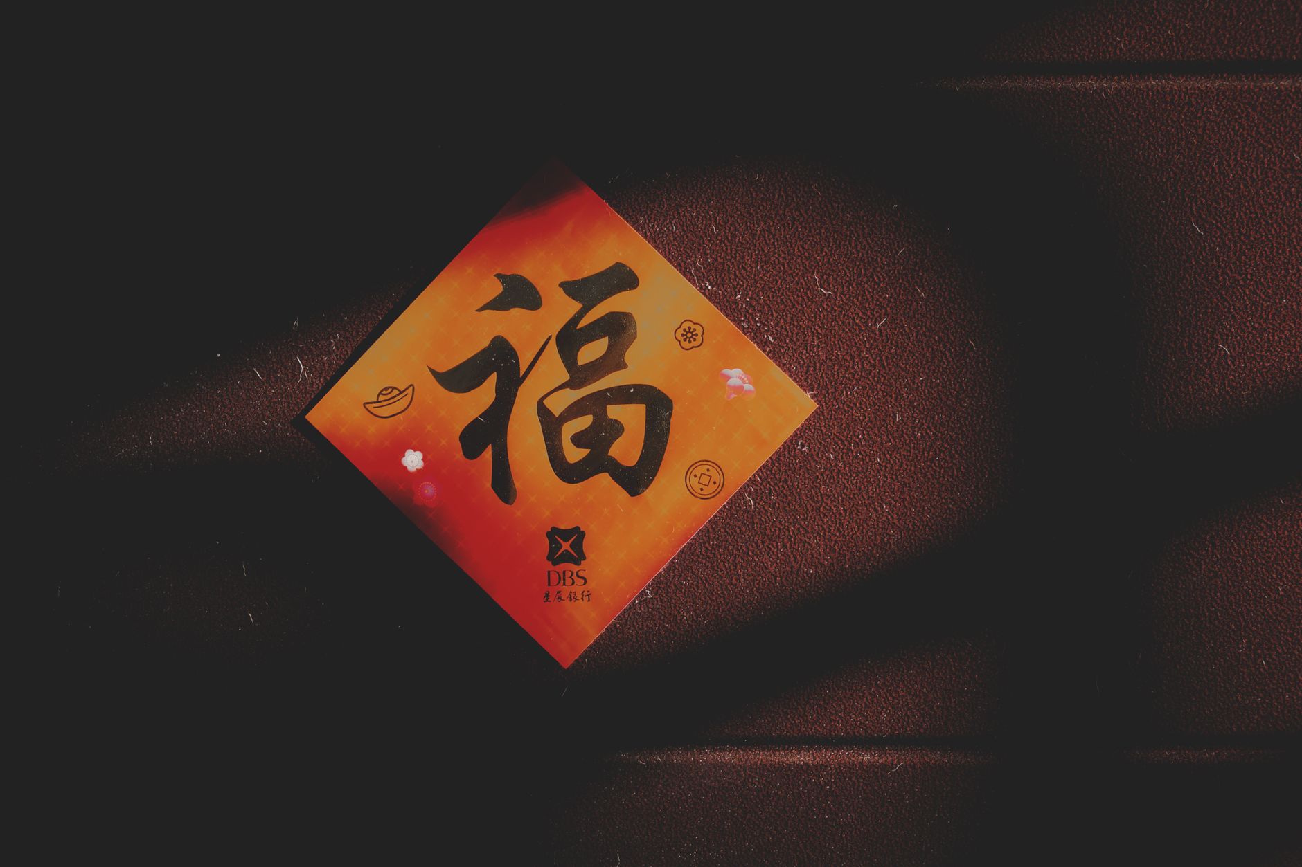 Close-up of a Chinese character card on a textured brown wall with shadows.