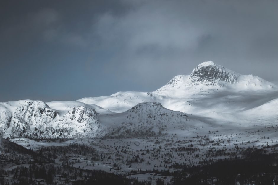 A breathtaking view of a snow-covered mountain range under a cloudy winter sky.