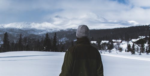 Free Man With Black Jacket and Grey Knit Cap Standing on White Snow Field Stock Photo
