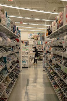 A woman browsing colorful craft supplies in a supermarket aisle.