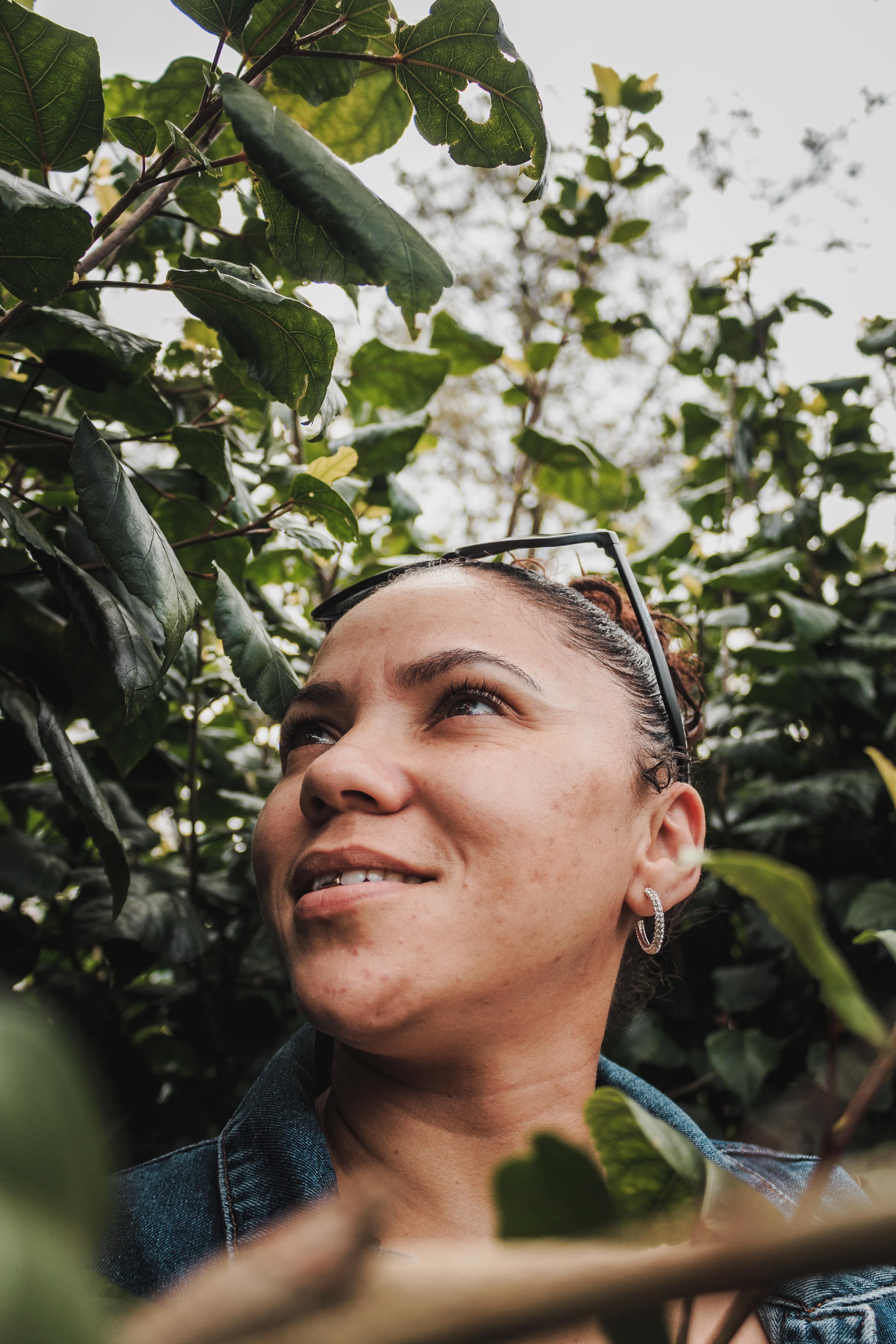 A person smiling and looking confidently into the distance, surrounded by nature