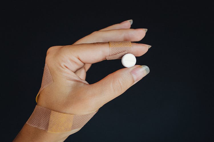 A Person's Hand Holding A White Tablet