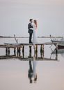 A Newly Wed Couple Standing on a Wooden Dock while Facing Each Other