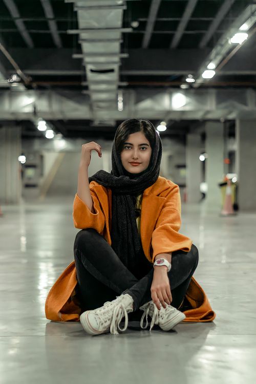 Free Portrait of a young woman in hijab sitting in a modern indoor parking area. Stock Photo