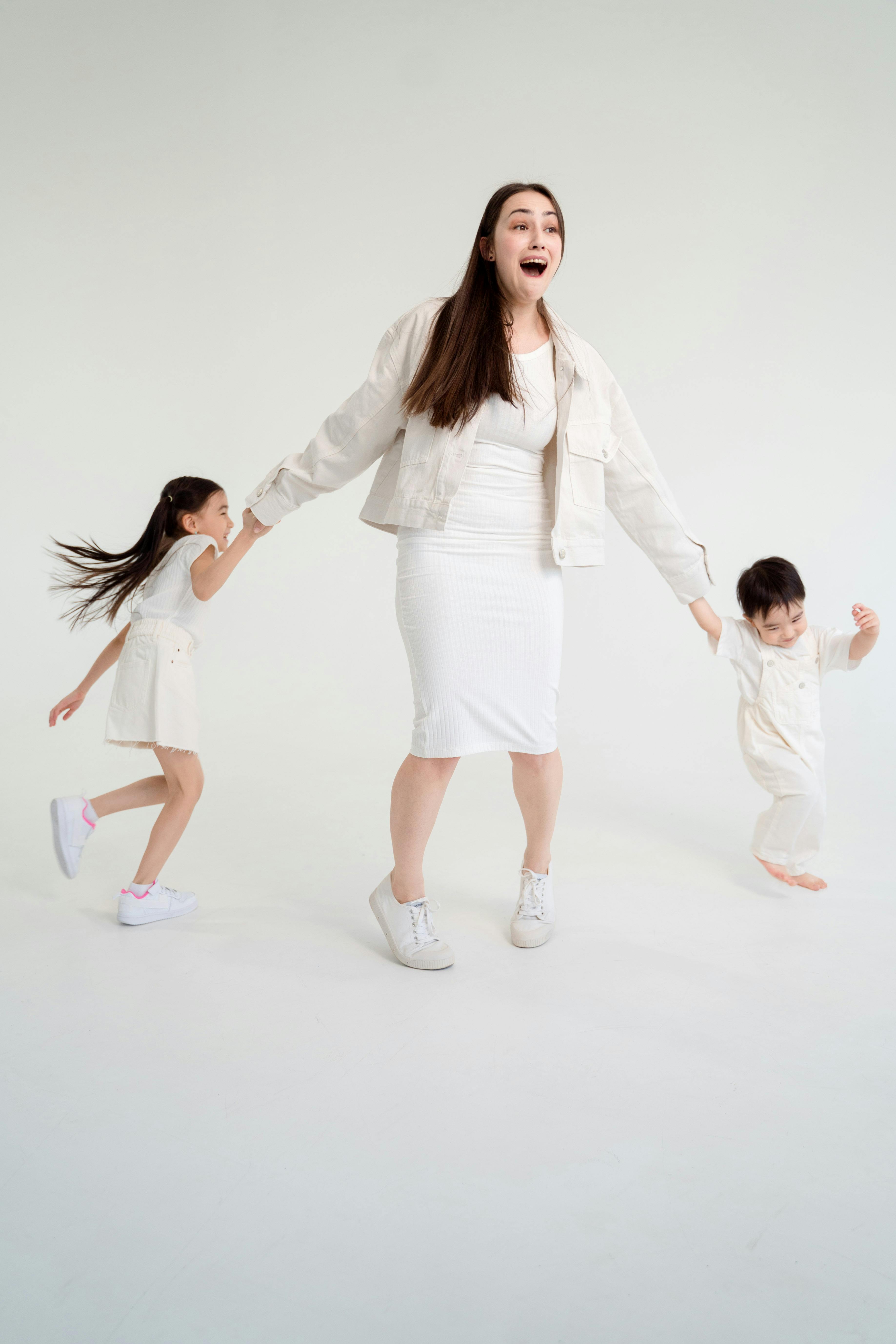 woman in white blazer and white dress shirt holding girl in white dress