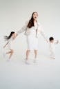 Woman in White Blazer and White Dress Shirt Holding Girl in White Dress