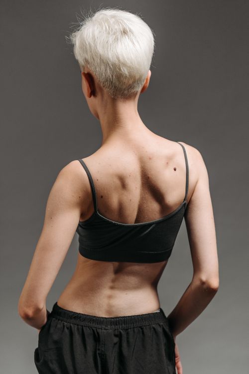 Free Studio shoot of a woman with short gray hair standing in a minimalist setting, rear view. Stock Photo