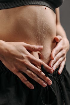 Hands resting on a toned stomach in sportswear, reflecting fitness and health.