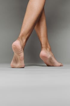 Close-up of bare feet crossing on a gray background in a studio setting.