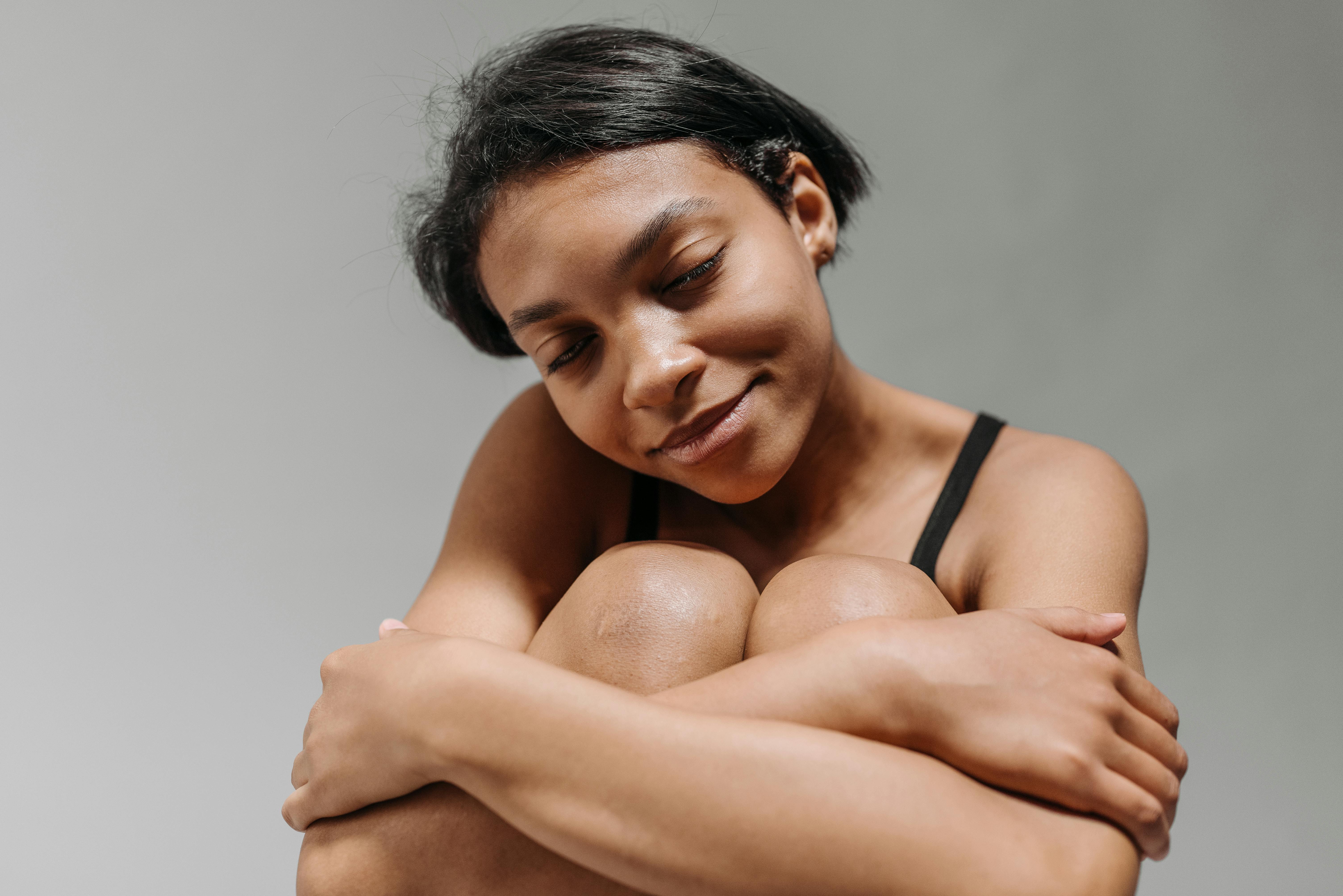 Close-up portrait of a young black woman with eyes closed, looking serene and content.