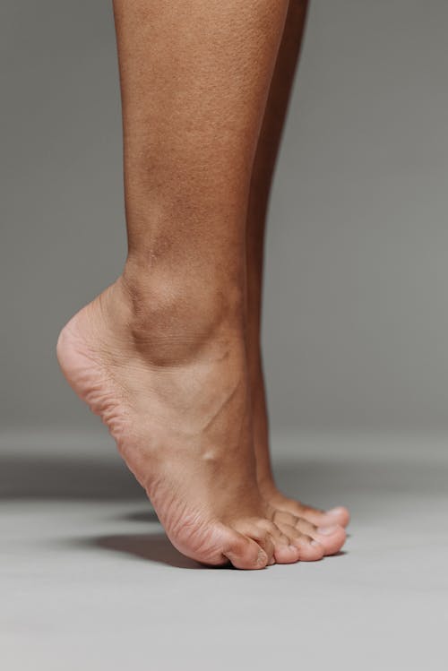 A Barefooted Person Tiptoeing on a White Surface