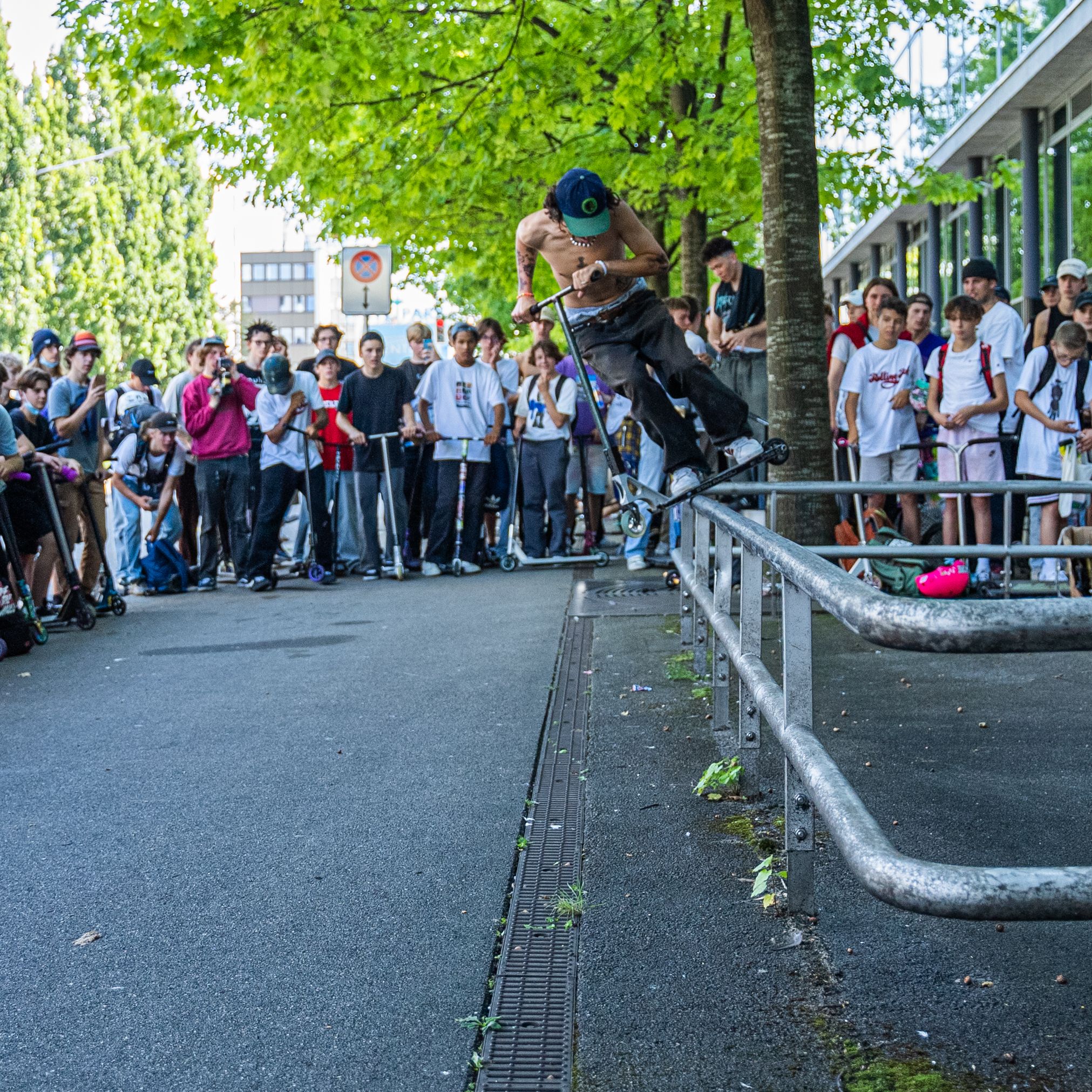 A thrilling scooter trick performed on a rail in a lively urban crowd.