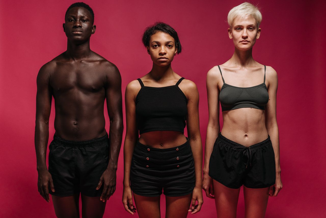three diverse individuals stand confidently against a pink background