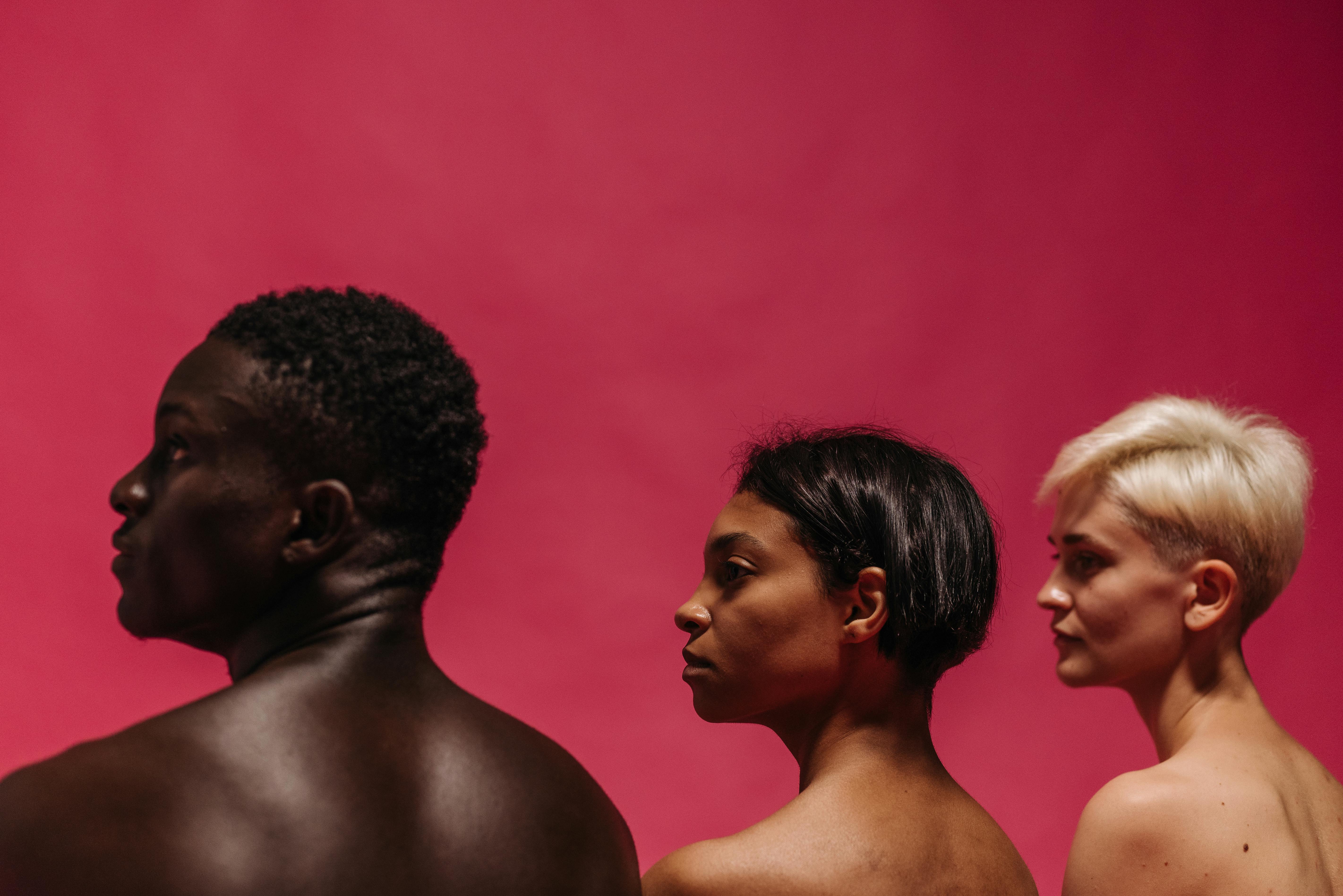 Artistic profile portrait of three diverse individuals against a bold red backdrop.