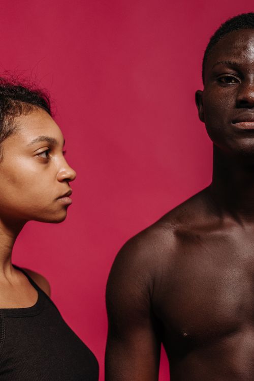 Free Side view portrait of a young couple against a vibrant pink backdrop. Stock Photo