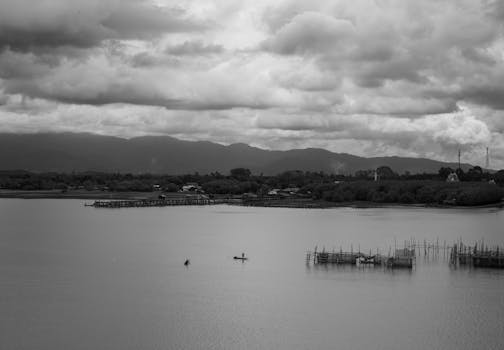 A black and white aerial view of a peaceful river with fishing boats in Chanthaburi, Thailand.