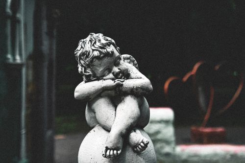 Free Close-up of a serene stone cherub statue in a tranquil outdoor setting, evoking peace and calmness. Stock Photo