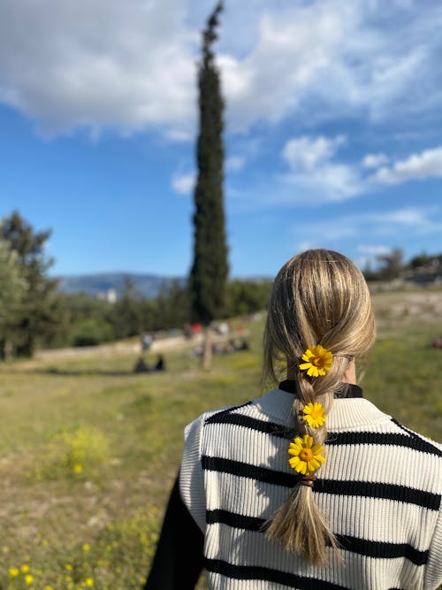 Back View of a Woman in a Sweater Vest with Yellow Flowers on Her Hair