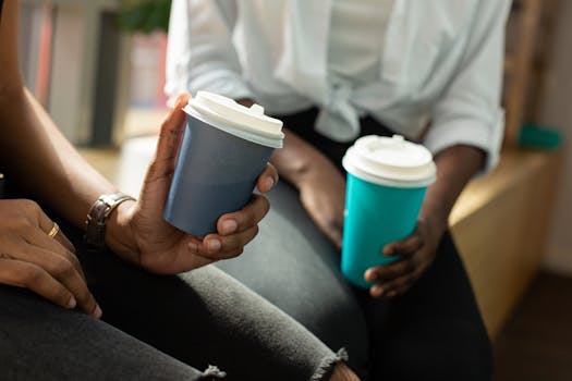 Two people holding reusable coffee cups in a cozy indoor setting.