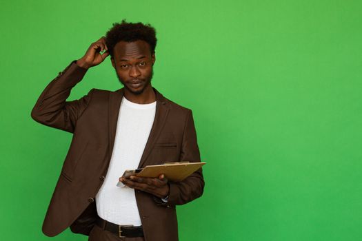 African American man scratching his head while holding a clipboard, studio shot.