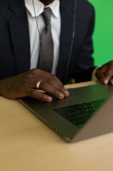 Close-up of a professional typing on a laptop in an office environment.