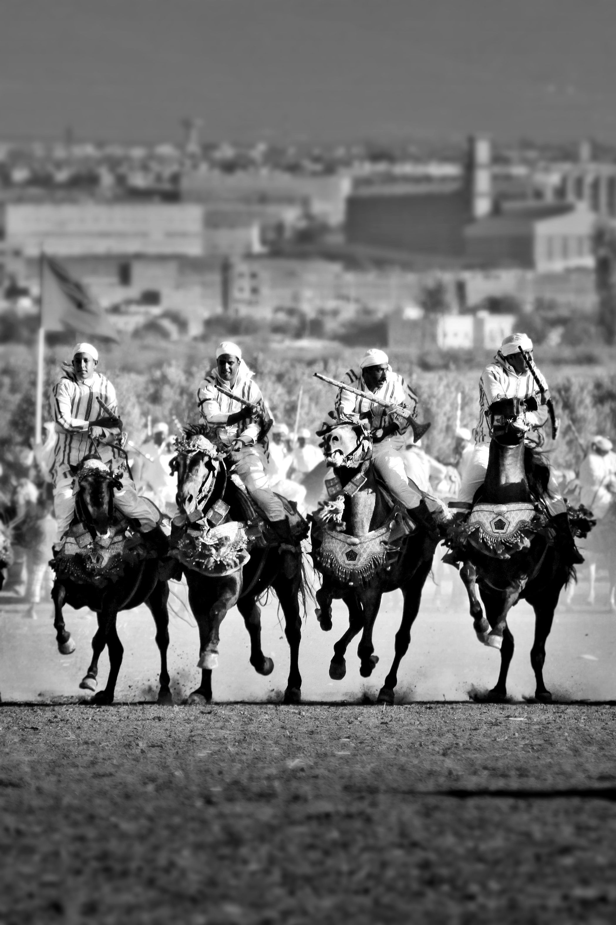 Black and white photo of Moroccan cavalrymen in traditional attire performing a synchronized charge.
