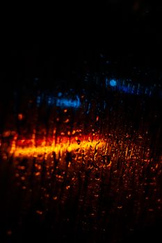 Vibrant abstract of raindrops on glass with blue and orange lights.