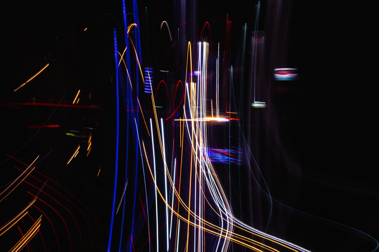 abstract image of colorful light streaks forming patterns on a dark ba