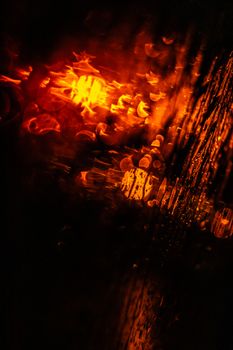 Abstract image of water droplets on a window with glowing orange light creating a blurred effect.