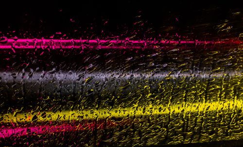 Free Colorful neon lights seen through rain-covered glass create a vivid and abstract texture. Stock Photo
