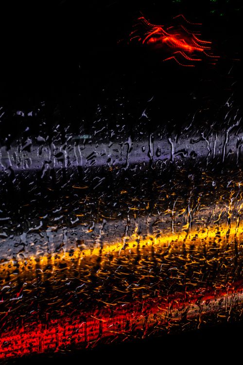 Free Abstract image of rain on window with vibrant traffic light reflections at night. Stock Photo