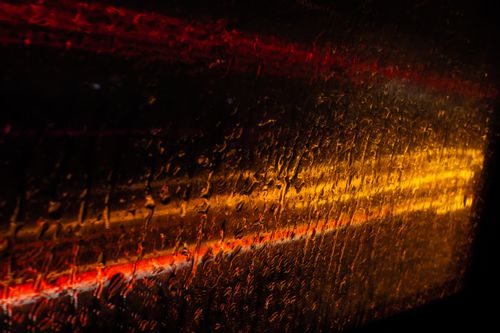 Free Abstract view of raindrops on window with blurred red and yellow city lights at night. Stock Photo