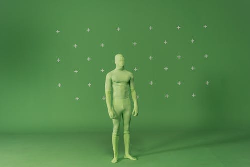 A Person in Green Zentai Costume Standing Near Green Wall