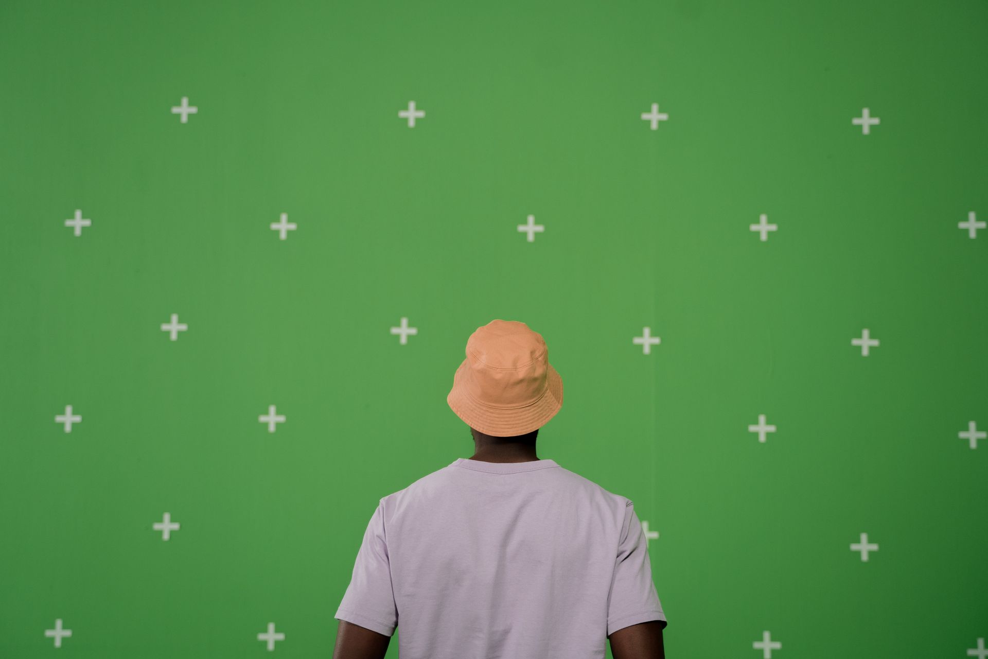 Back View of a Man Facing a Green Wall with Crosses