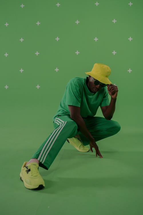 Man in Green Shirt and White and Green Pants Sitting on Green Surface