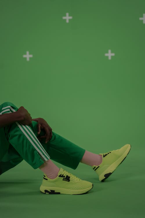 A Person in Green Jogging Pants and Green Sneakers Sitting on the Floor