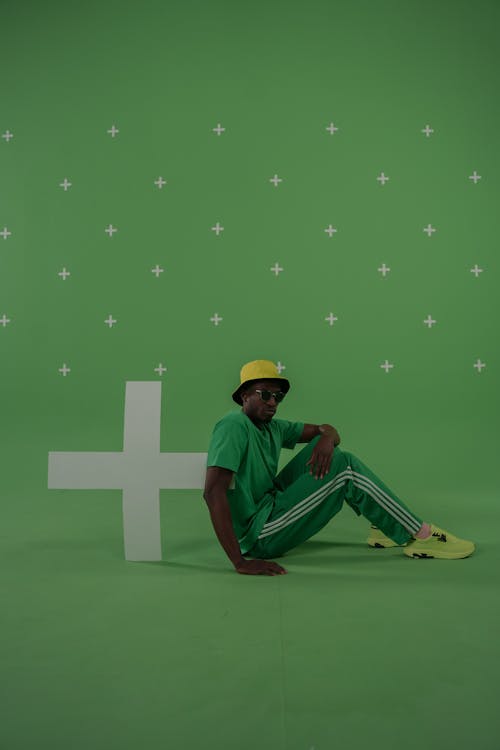 A Man in Green Clothes Sitting on Green Surface