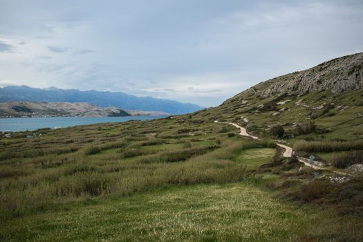 Stunning coastal landscape of Pag in Croatia featuring hills and the Adriatic Sea under a cloudy sky.