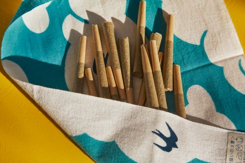 Free Collection of cannabis joints on blue and white patterned fabric, sunny setting. Stock Photo