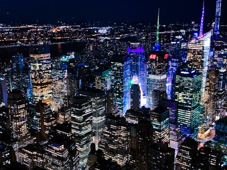 Vibrant aerial view of New York City's skyline at night, showcasing illuminated skyscrapers.
