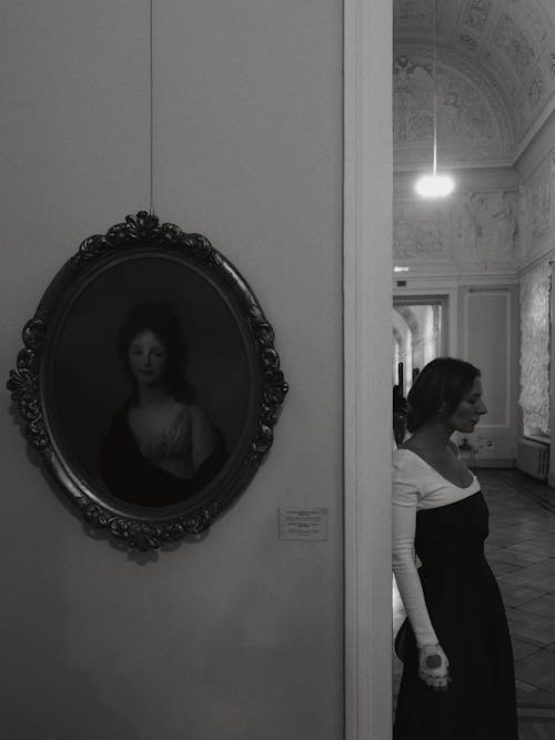 Grayscale Photography of a Woman Leaning on the Wall while Looking Afar