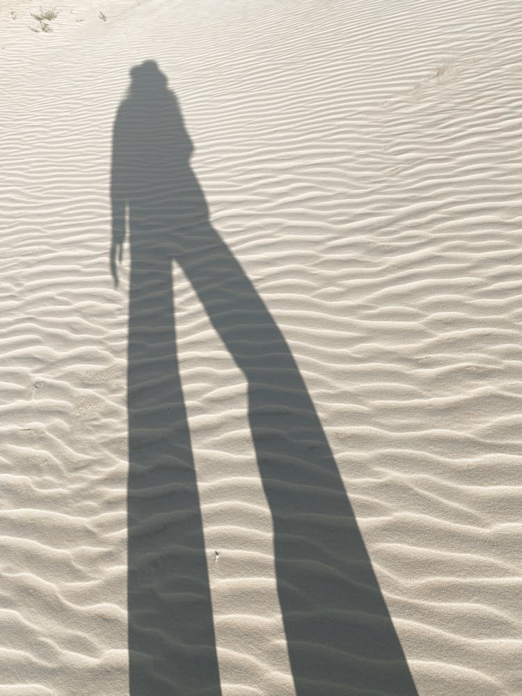 A Shadow Of A Person On The Sandy Ground