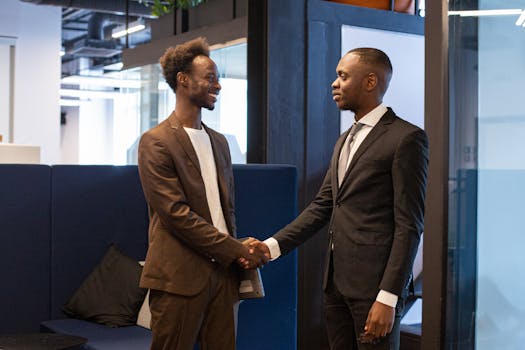 Two professional men shaking hands in a modern office setting, symbolizing successful business collaboration.