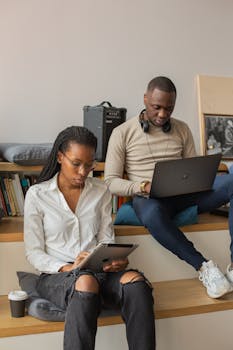 Two professionals working with digital devices in a modern office setting.